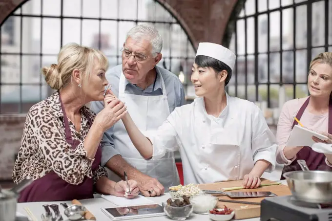 Senior woman smelling ingredient in cooking class