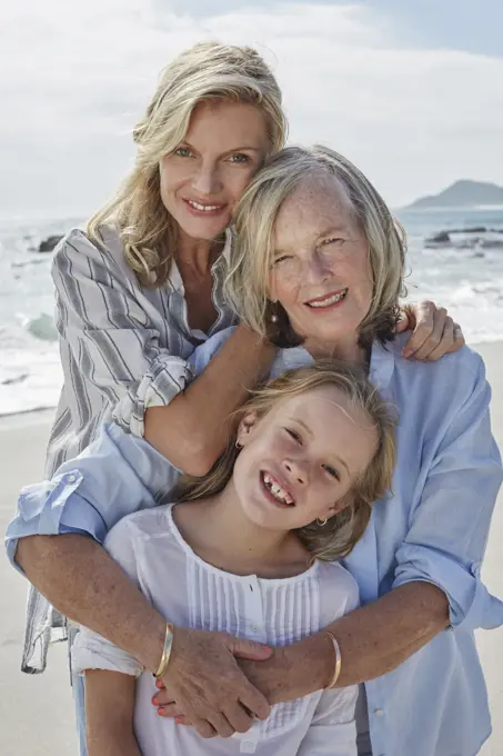 Mother, daughter and grandmother embracing on the beach