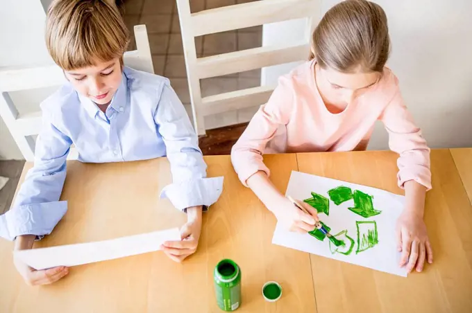 Brother and sister painting recycling symbols