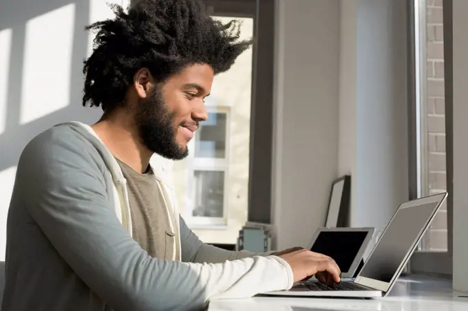 Man working in front of window at home with laptop