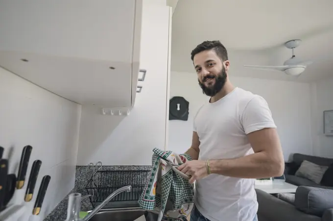 Young man doing the dishes in the kitchen