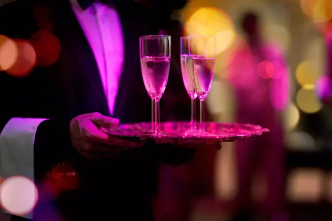 Waiter with tray serving champagne glasses on a party