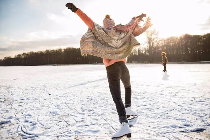 Rear view of woman with ice skates on frozen lake