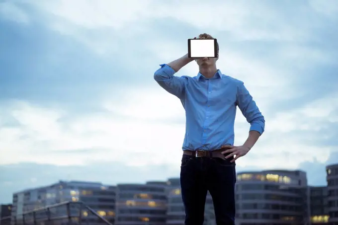 Man hiding his face behind mini tablet