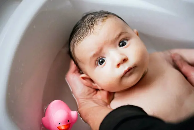 Woman bathing baby in a tub