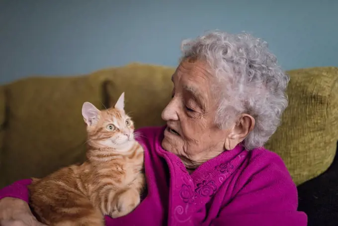 Senior woman sitting with tabby cat on the couch