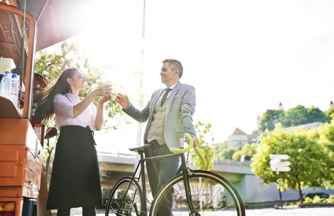 Businessman with bicycle buying take away coffee on the street