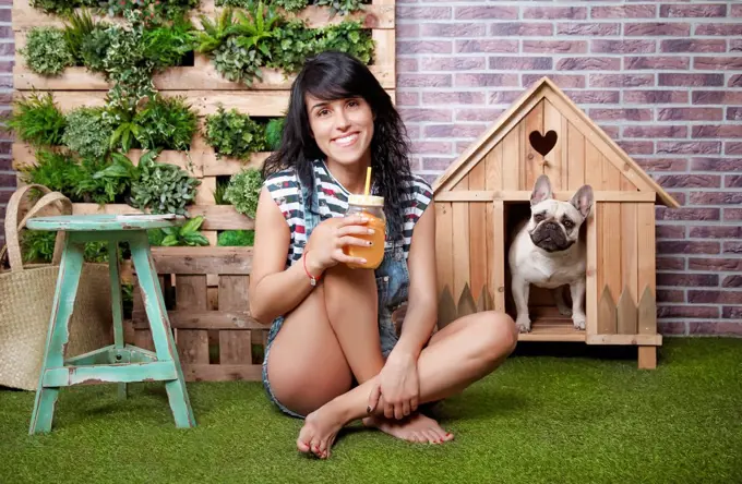 Woman and french bulldog in front of dog house and vertical garden