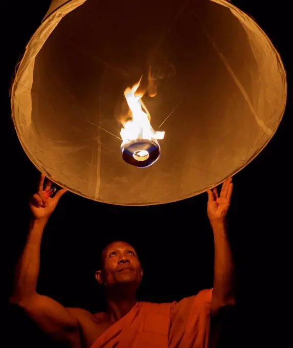 Thailand, Chiang Mai, Buddhist monk lighting lantern