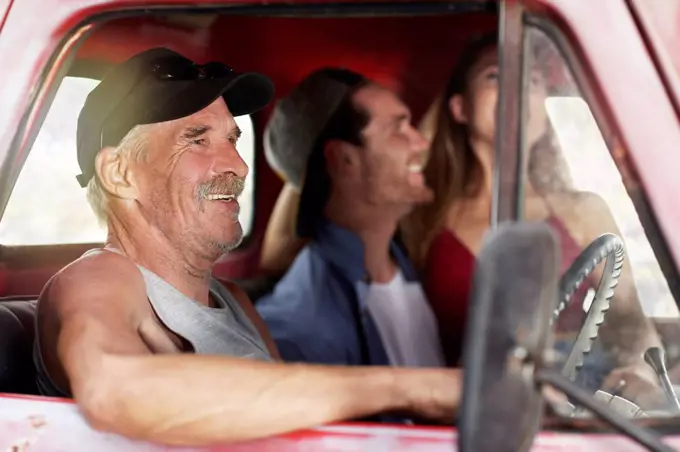 Happy senior man and young couple in an old pick up