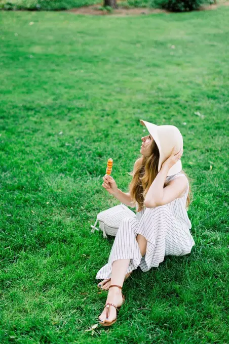 Woman sitting on meadow earing popsicle