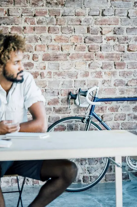 Young man at desk thinking with bicycle in background