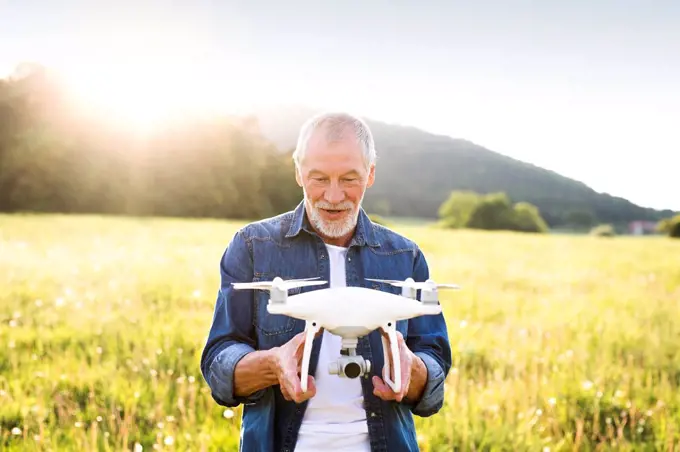 Portrait of senior man with drone on a meadow