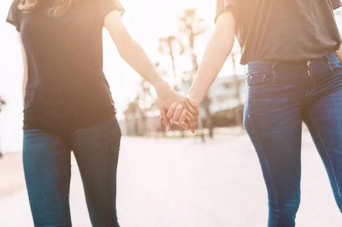 Two young women walking hand in hand on the boardwalk