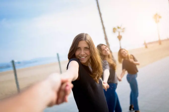 Happy young women holding hands outdoors