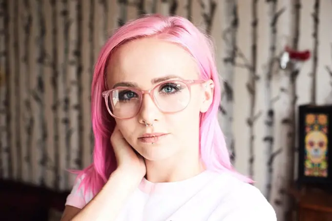 Portrait of young woman with pink hair, glasses and piercings