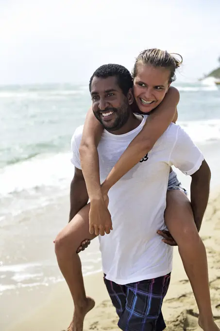 Man giving girlfriend piggyback ride on the beach