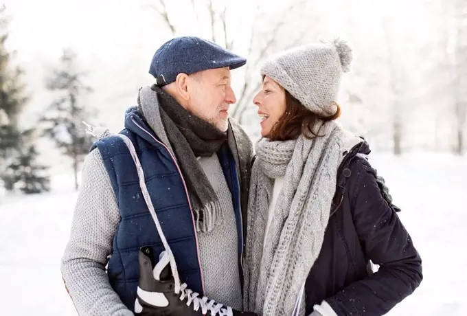 Senior couple with ice skates in winter landscape