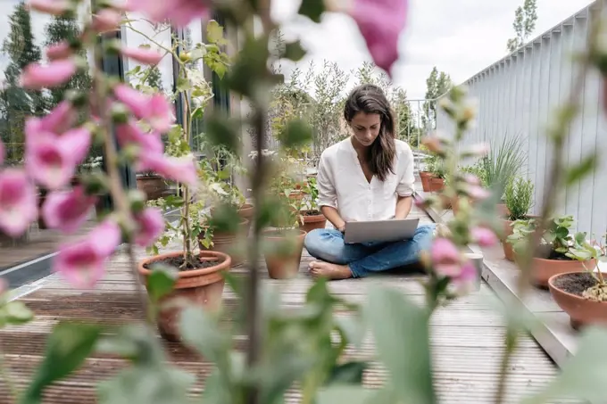 Woman sitting on balcony using laptop