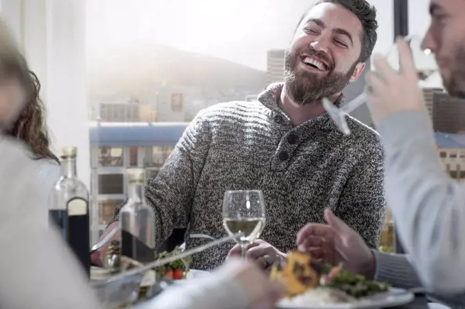 Man laughing at dinner table with friends