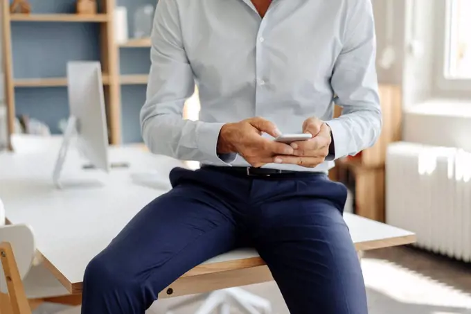 Close-up of businessman in office using cell phone