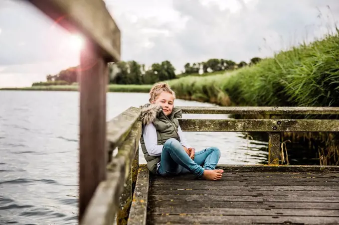 Girl sitting on jetty at a lake