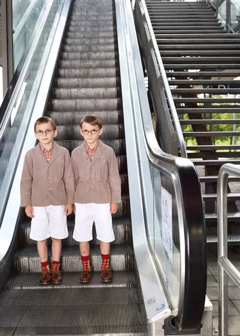 Twin brothers standing on escalator