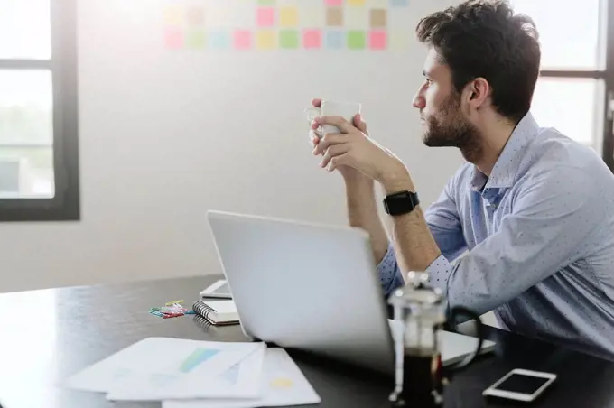 Young businessman working in office, drinking coffee