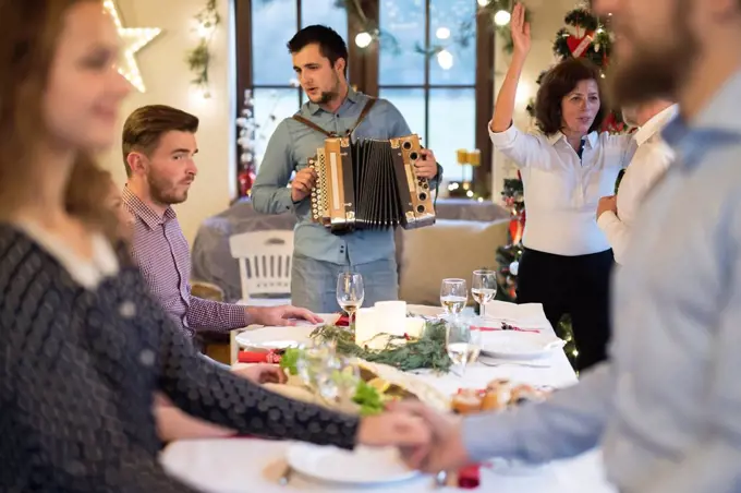 Young man playing accordion for family at Christmas