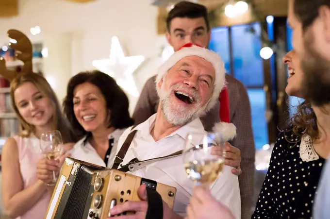 Senior man playing accordion for happy family at Christmas