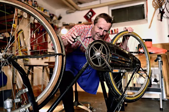 Senior man checking bicycle in his workshop