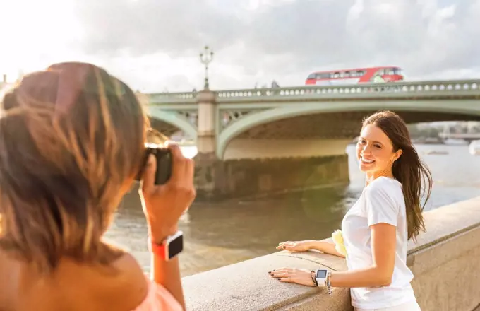 UK, London, woman taking a picture of her friend near Westminster Bridge