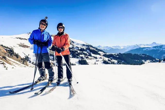 Austria, Damuels, couple with action cam skiing in winter landscape