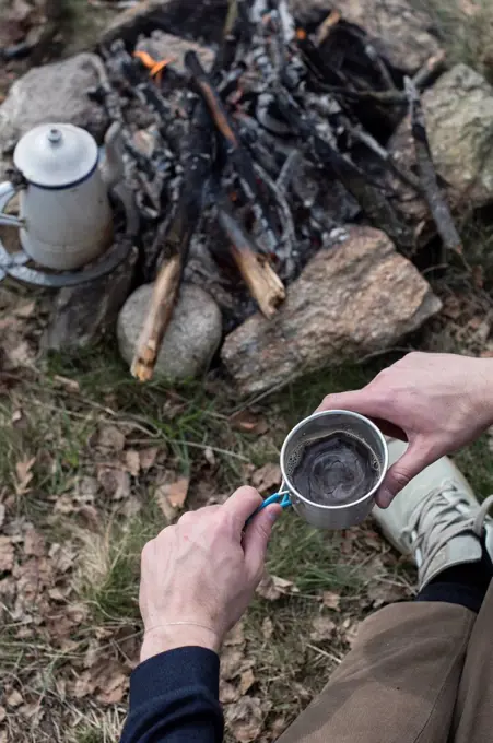 Man drinking coffee at campfire