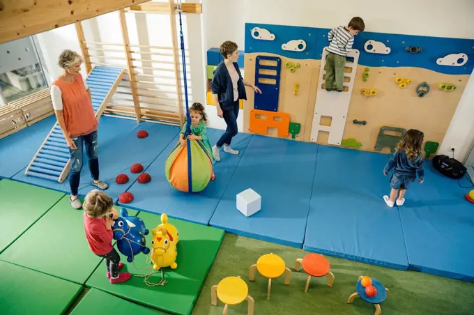 Pre-school teachers and children in gym room in kindergarten