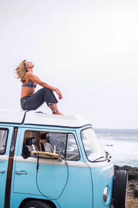 Spain, Tenerife, young woman sitting on car roof of van