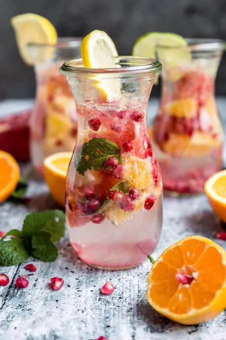 Detox water, glass of infused water with citrus fruits, pomegranate seed and mint