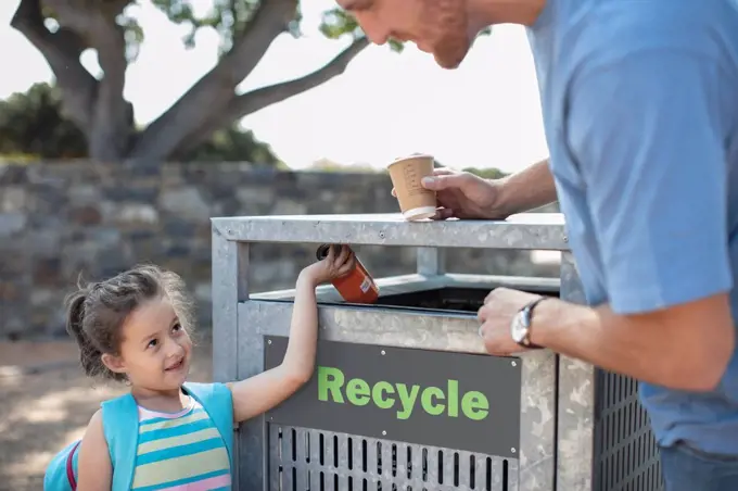 Girl with father putting a drink can in a recycle bin