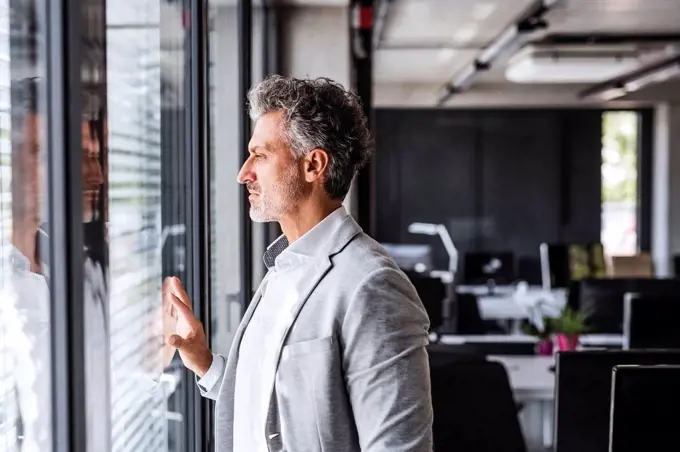 Mature businessman in office loooking out of window