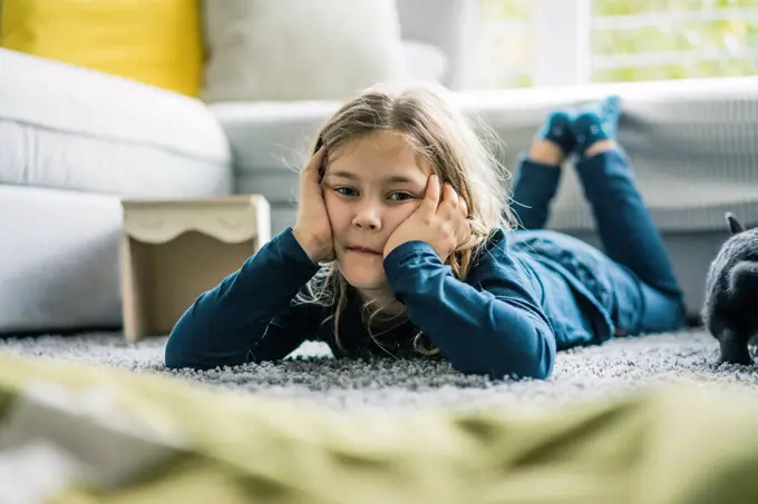 Portrait of girl lying with hare in living room