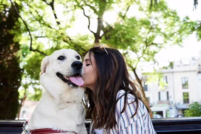 Young woman kissing her dog