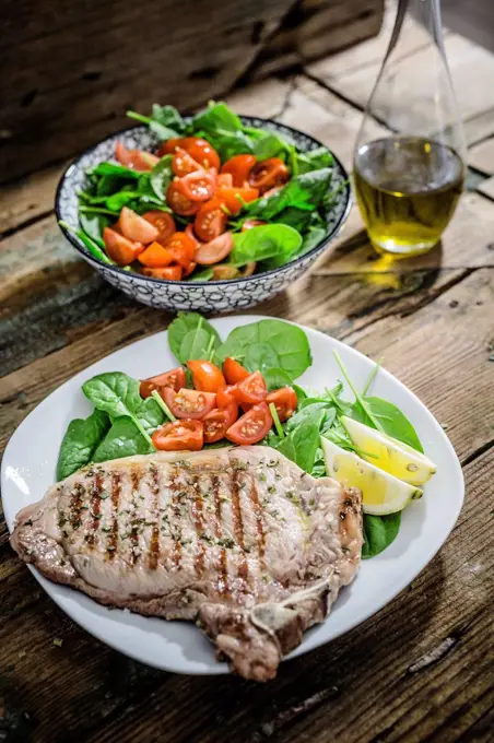 Roasted beefsteak with rosemary, spinach salad with tomato, lemon