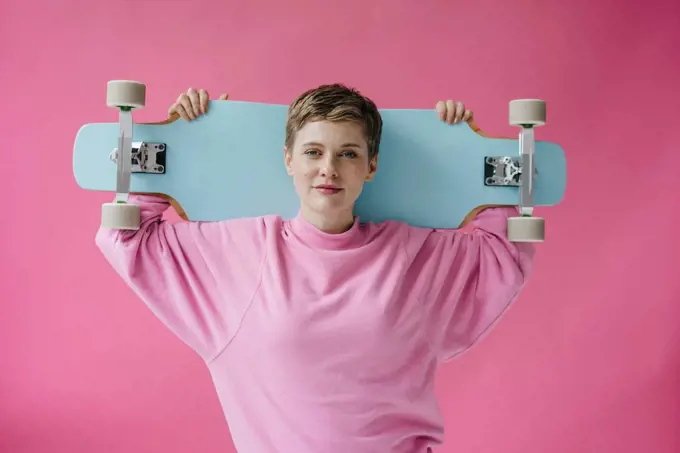 Portrait of woman in pink holding skateboard