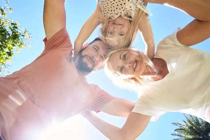 Portrait of happy family huddling under blue sky