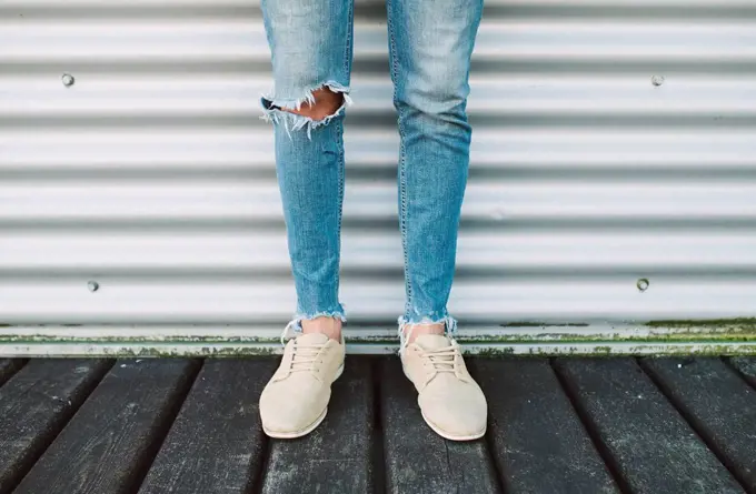 Legs of man wearing torn jeans