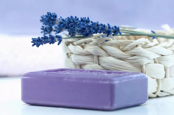 Twig of lavender on a basket and a piece of lavender soap