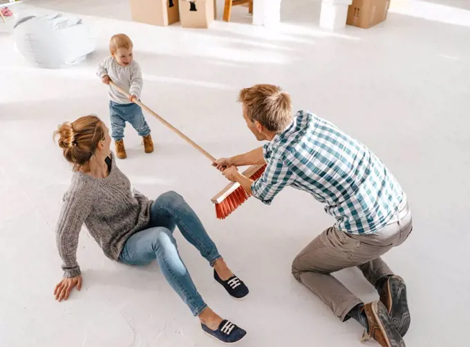 Father and daughter having fun with a broom in a loft