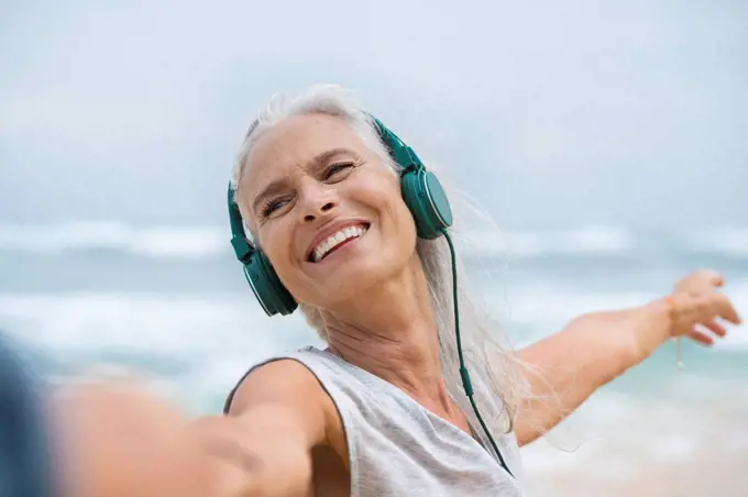 Portrait of beautiful smiling senior woman dancing on beach