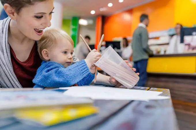 Little boy with mother drawing at table in pharmacy