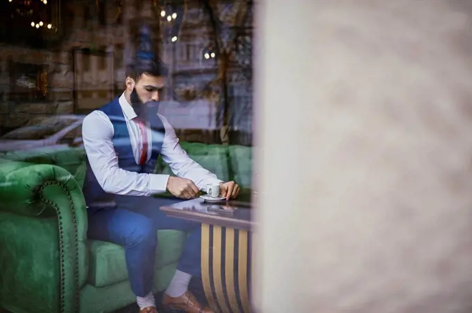 Fashionable young man sitting on couch in a cafe